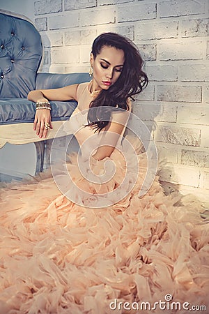 Beautiful lady in gorgeous couture dress on sofa Stock Photo