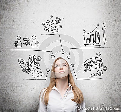 Beautiful lady is thinking about business development measures. Charts, pie chart, business icons are drawn on the concre Stock Photo