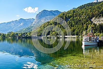 Beautiful landscape with lake, boat, mountain, forest and reflection on the water in Austrian Alps. Wallpaper. Stock Photo