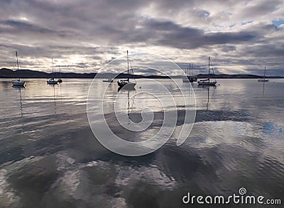 Beautiful landscape of a lake with silhouettes of boats under a cloudy sky Stock Photo