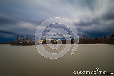 Beautiful landscape before the storm. Bird island in the middle of the pond. Dramatic clouds Stock Photo