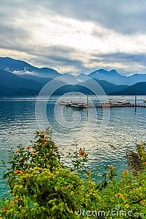 Beautiful Landscape of Sun Moon Lake in the morning with mountain background and yellow flower foreground at Nantou, Taiwan Editorial Stock Photo