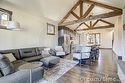 Beautiful large bright vaulted ceiling with large wooden beams and white walls living room interior with stone and leather sofa Stock Photo