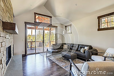 Beautiful large bright vaulted ceiling with large wooden beams and white walls living room interior with stone and leather sofa Stock Photo