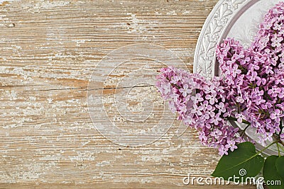 Beautiful lilac flowers lying on a silver saucer against the background of an old wooden plank with a texture paint Stock Photo