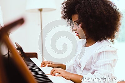 African American girl smile happy playing and learning piano classroom in holiday weekend at home. Stock Photo