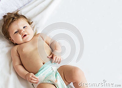 Beautiful little baby lying on a white diaper. Stock Photo