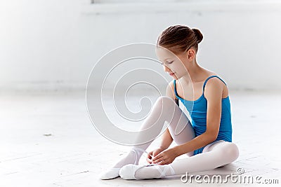 Beautiful little ballerina in blue dress for dancing puting on foot pointe shoes Stock Photo