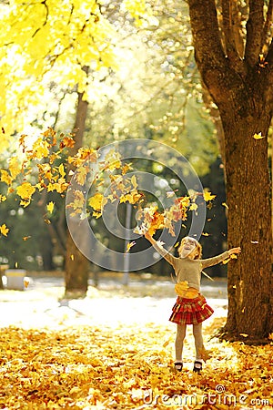 Beautiful little girl in the autumn park playing in nature Stock Photo