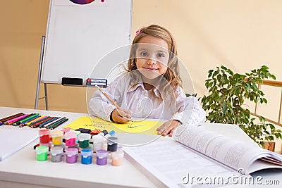 Beautiful little girl draws sitting at table Stock Photo