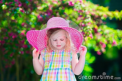Beautiful little girl in a hat in blooming summer garden Stock Photo