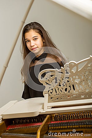 The girl is at the white grand piano. Stock Photo