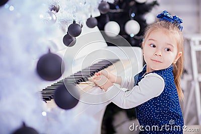 Beautiful little girl piano and looking at camera Stock Photo