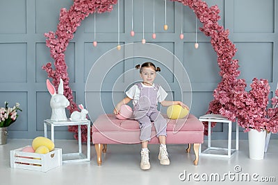 Beautiful little girl playing with colorful Easter eggs and Easter bunny. Easter interior room. Family holidays, traditions. Harve Stock Photo
