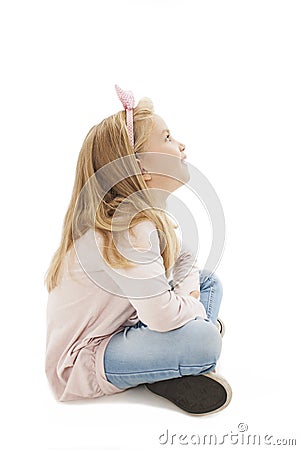 Beautiful little girl sitting on floor, looking on copy space Stock Photo