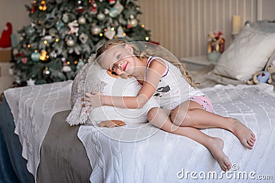 Beautiful little girl sitting near the Christmas tree. Stock Photo