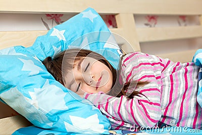 Beautiful little girl sleep in bed under a blue blanket Stock Photo