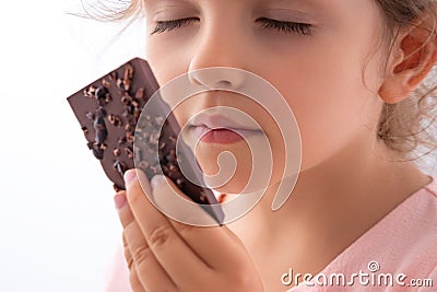 Beautiful little girl taste chocolate like a pro - breaking cacao bar, smelling, eating Stock Photo