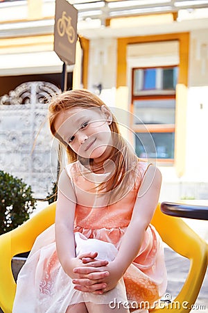 Beautiful little girl wear in fashion dress sitting in a cafe Stock Photo