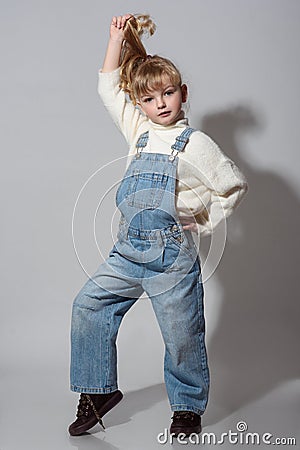 Beautiful little girl wearing stylish denim overall, white roll neck fluffy jumper posing on white background Stock Photo