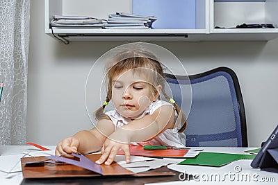 Beautiful little girl in a white blouse cuts out of paper. children`s creativity Stock Photo