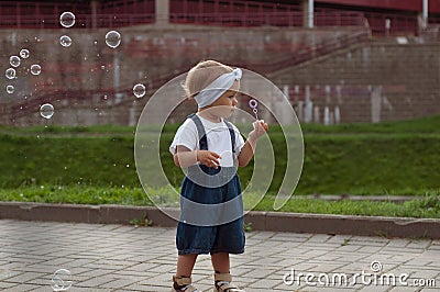 Beautiful little haired hair girl, has happy fun smiling face, pretty eyes, short hair, playing soap bubbles in white t Stock Photo