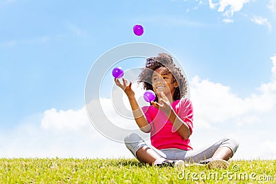 Positive happy girl juggle balls on the grass Stock Photo