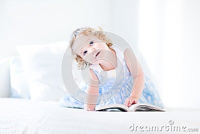 Beautiful little toddler girl with curly hair reading book Stock Photo