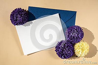 Beautiful little violet flowers on postal blue envelope on beige background, empty paper note copy space for text Stock Photo