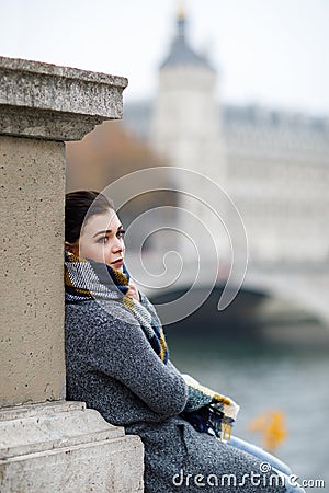 Beautiful lonely brunette girl in Paris, standing alone in a gray coat Stock Photo