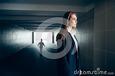Beautiful lonely woman in subway tunnel with frighten silhouette Stock Photo
