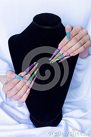 Beautiful long colorful false nails on a white background and black base , the nails for the exhibition Stock Photo