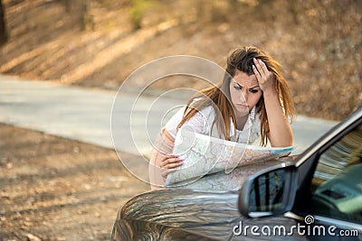 Beautiful lost woman looking at a map on the side of the road Stock Photo