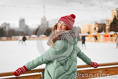 Beautiful lovely middle-aged girl with curly hair warm winter jackets stands ice rink background Town Square Stock Photo