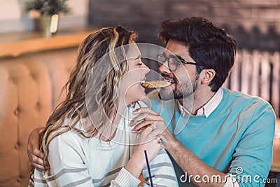 Beautiful loving couple sitting in a cafe sharing cookie. Stock Photo