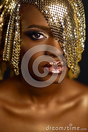 Beautiful Magic Woman Portrait. Golden Makeup. Model Afro-american Girl face with gold skin, lips, make-up and accessories Stock Photo