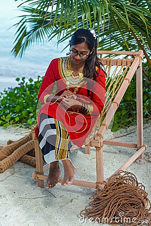 Beautiful maldivian woman in national dress making hand made rope Editorial Stock Photo