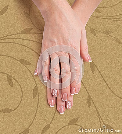 Beautiful manicure. Hands of a woman on a stylish beige background with a floral pattern Stock Photo