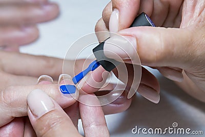 Beautiful manicure process. Nail polish being applied to hand, polish is a blue color. close up Stock Photo