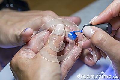 Beautiful manicure process. Nail polish being applied to hand, polish is a blue color. close up Stock Photo