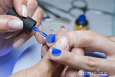 Beautiful manicure process. Nail polish being applied to hand, polish is a blue color. close up Stock Photo