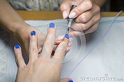 Beautiful manicure process. Nail polish being applied to hand, polish is a blue color. close up Stock Photo