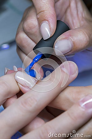 Beautiful manicure process. Nail polish being applied to hand, polish is a blue color. closeup. vertical photo Stock Photo