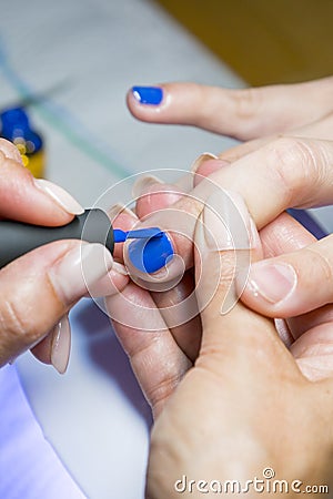 Beautiful manicure process. Nail polish being applied to hand, polish is a blue color. closeup. vertical photo Stock Photo