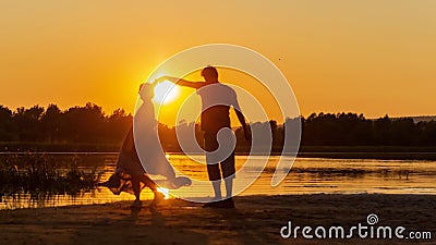 Beautiful mature couples dance on a wild beach in the rays of the setting sun Stock Photo