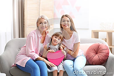 Beautiful mature lady, daughter and grandchild with gift at home. Happy Women`s Day Stock Photo