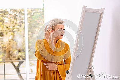 Beautiful mature woman looking at herself in large mirror Stock Photo