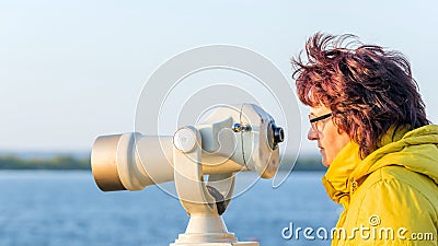 Beautiful mature woman looking through a telescope watching Stock Photo