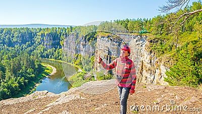 beautiful mature women sits on a high rock above the river and admires the big Aisian cliffs Stock Photo