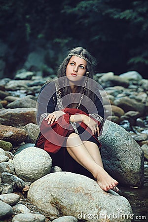 Beautiful medieval woman seated on rocks Stock Photo